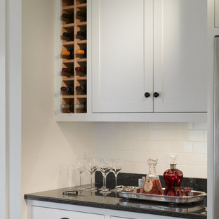 This is an example of a large country u-shaped eat-in kitchen in Burlington with an undermount sink, shaker cabinets, white cabinets, granite benchtops, black splashback, stone slab splashback, stainless steel appliances, light hardwood floors and with island.