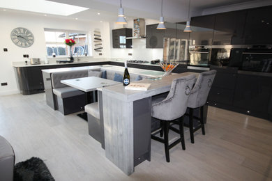 Immagine di una grande cucina minimalista con lavello integrato, ante lisce, ante grigie, top in quarzite, paraspruzzi bianco, elettrodomestici in acciaio inossidabile, pavimento in vinile, pavimento grigio e top bianco