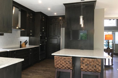 Open concept kitchen - mid-sized transitional u-shaped medium tone wood floor and brown floor open concept kitchen idea in Calgary with raised-panel cabinets, dark wood cabinets, quartzite countertops, white backsplash, ceramic backsplash, stainless steel appliances and a peninsula