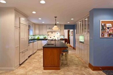 Photo of a large country u-shaped kitchen/diner in Philadelphia with a submerged sink, recessed-panel cabinets, white cabinets, soapstone worktops, white splashback, ceramic splashback, integrated appliances, lino flooring and an island.