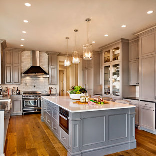 Design ideas for a large traditional u-shaped eat-in kitchen in Portland with a farmhouse sink, recessed-panel cabinets, quartz benchtops, subway tile splashback, panelled appliances, medium hardwood floors, with island, beige cabinets, grey splashback and brown floor.