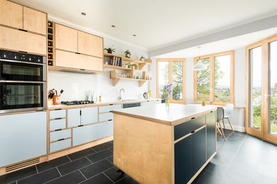 Photo of a medium sized nautical single-wall kitchen/diner in Edinburgh with a single-bowl sink, wood worktops, white splashback, glass sheet splashback, stainless steel appliances, an island and grey worktops.