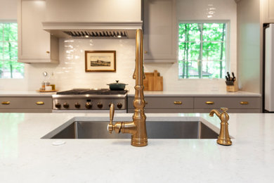 Medium sized farmhouse galley kitchen/diner in Chicago with a submerged sink, shaker cabinets, grey cabinets, engineered stone countertops, yellow splashback, ceramic splashback, stainless steel appliances, medium hardwood flooring, brown floors, white worktops, exposed beams and multiple islands.