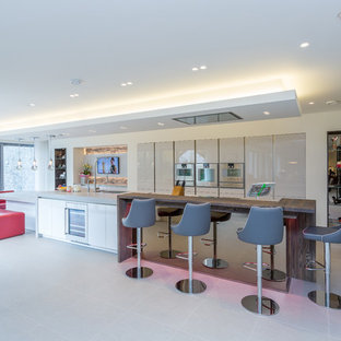 Photo of a contemporary galley kitchen in Manchester with a submerged sink, flat-panel cabinets, beige cabinets, stainless steel appliances, an island, grey floors and grey worktops.