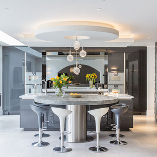 This is an example of a large contemporary eat-in kitchen in Manchester with a drop-in sink, grey cabinets, granite benchtops, metallic splashback, glass sheet splashback, stainless steel appliances, porcelain floors, multiple islands, grey floor and white benchtop.