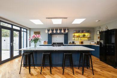 This is an example of a medium sized traditional l-shaped open plan kitchen in Other with shaker cabinets, blue cabinets, laminate countertops, white splashback, an island and white worktops.