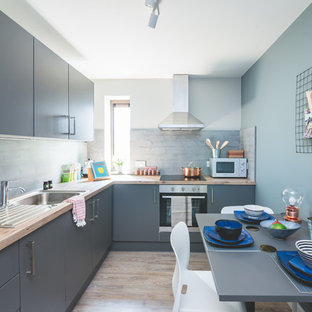 This is an example of a contemporary l-shaped kitchen/diner in Other with a built-in sink, flat-panel cabinets, grey cabinets, grey splashback, brown floors and brown worktops.