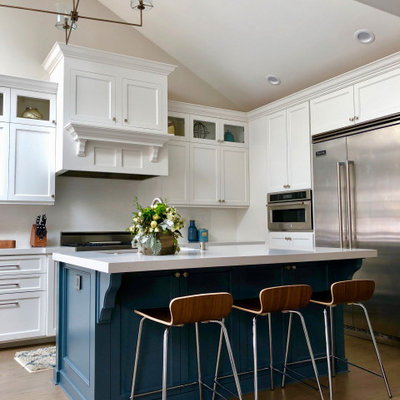 Transitional l-shaped medium tone wood floor and brown floor kitchen photo in San Diego with shaker cabinets, white cabinets, stainless steel appliances, an island and white countertops