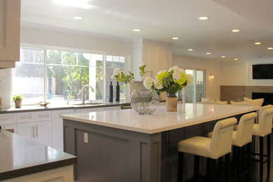 Example of a mid-sized transitional u-shaped dark wood floor and black floor eat-in kitchen design in Los Angeles with an undermount sink, raised-panel cabinets, gray cabinets, gray backsplash, ceramic backsplash, stainless steel appliances, an island, concrete countertops and gray countertops