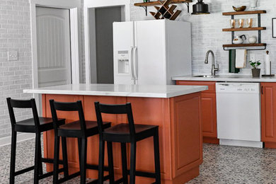 Mid-sized tuscan single-wall porcelain tile and blue floor eat-in kitchen photo in Atlanta with a single-bowl sink, raised-panel cabinets, orange cabinets, laminate countertops, white backsplash, brick backsplash, white appliances, an island and gray countertops