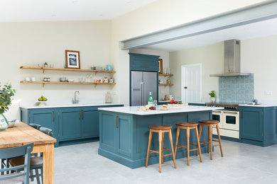 Photo of a medium sized traditional l-shaped kitchen/diner in London with shaker cabinets, blue cabinets, quartz worktops, an island and white worktops.