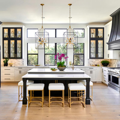 Example of a large classic light wood floor kitchen design in Austin with quartz countertops, stainless steel appliances, an island, white countertops, window backsplash and raised-panel cabinets