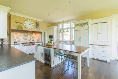 Example of a mid-sized farmhouse l-shaped medium tone wood floor and brown floor eat-in kitchen design in DC Metro with a farmhouse sink, flat-panel cabinets, white cabinets, granite countertops, white backsplash, stainless steel appliances, an island and gray countertops