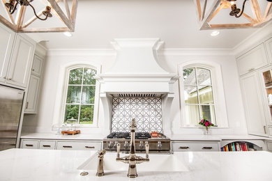 Large transitional u-shaped medium tone wood floor and brown floor enclosed kitchen photo in Other with a farmhouse sink, recessed-panel cabinets, white cabinets, marble countertops, stainless steel appliances, an island and white countertops