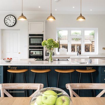 Stunning white kitchen with large dark blue island and marble worktops
