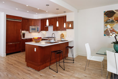 Eat-in kitchen - mid-sized modern u-shaped laminate floor and gray floor eat-in kitchen idea in Orange County with a single-bowl sink, shaker cabinets, dark wood cabinets, quartz countertops, white backsplash, paneled appliances, an island and white countertops