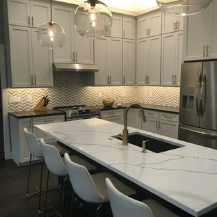 Expansive transitional l-shaped open plan kitchen in Other with an undermount sink, shaker cabinets, white cabinets, quartz benchtops, white splashback, marble splashback, stainless steel appliances, vinyl floors, with island, brown floor and multi-coloured benchtop.