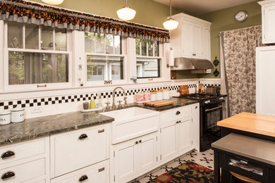 Eat-in kitchen - mid-sized traditional ceramic tile eat-in kitchen idea in Detroit with a farmhouse sink, shaker cabinets, white cabinets, granite countertops, black backsplash, subway tile backsplash, black appliances and an island