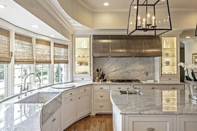 Example of a mid-sized transitional l-shaped light wood floor and brown floor enclosed kitchen design in Austin with a farmhouse sink, recessed-panel cabinets, white cabinets, quartzite countertops, gray backsplash, stone slab backsplash, stainless steel appliances and an island