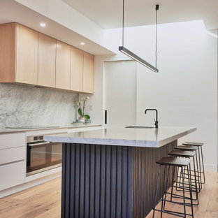 Mid-sized scandinavian galley open plan kitchen in Melbourne with a drop-in sink, grey splashback, stainless steel appliances, light hardwood floors and with island.