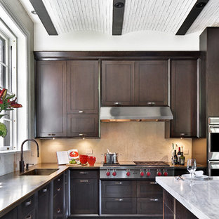 Photo of a large transitional u-shaped eat-in kitchen in Boston with an integrated sink, shaker cabinets, dark wood cabinets, beige splashback, stainless steel appliances, with island, marble benchtops, ceramic splashback and slate floors.