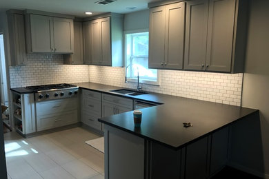 Example of a minimalist porcelain tile eat-in kitchen design in Houston with an undermount sink, flat-panel cabinets, gray cabinets, granite countertops, white backsplash, subway tile backsplash, stainless steel appliances and an island