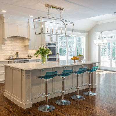 Example of a mid-sized transitional galley dark wood floor open concept kitchen design in Boston with an undermount sink, recessed-panel cabinets, white cabinets, white backsplash, subway tile backsplash, stainless steel appliances and an island