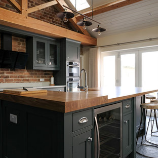 Design ideas for a traditional kitchen in Cheshire with quartz worktops, slate flooring, an island, glass-front cabinets, black cabinets, red splashback, brick splashback, black floors and grey worktops.