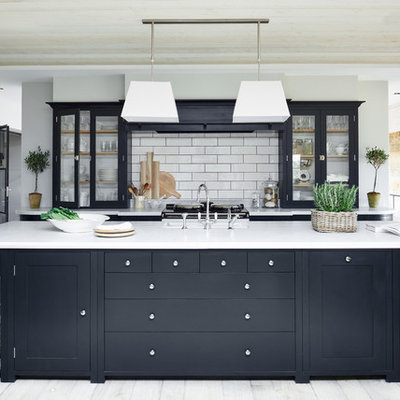 Transitional kitchen photo in London with glass-front cabinets, white backsplash, subway tile backsplash and an island