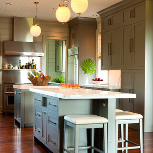 Design ideas for a tropical kitchen in Charleston with shaker cabinets, green cabinets, metallic splashback, medium hardwood floors, multiple islands, brown floor and white benchtop.