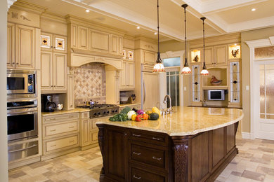 Example of a large classic single-wall ceramic tile and beige floor eat-in kitchen design in Houston with an undermount sink, raised-panel cabinets, light wood cabinets, granite countertops, beige backsplash, stone tile backsplash, stainless steel appliances and an island