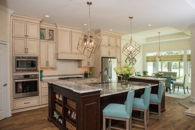 Mid-sized elegant l-shaped medium tone wood floor open concept kitchen photo in Atlanta with an undermount sink, raised-panel cabinets, distressed cabinets, granite countertops, white backsplash, subway tile backsplash, stainless steel appliances and an island