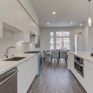 Open concept kitchen appliance - Example of a single-wall open concept kitchen design in San Francisco with an undermount sink, flat-panel cabinets, white cabinets, stainless steel appliances, an island and white countertops