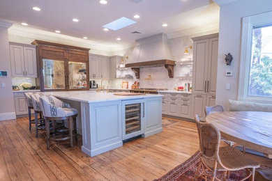 Inspiration for a large transitional medium tone wood floor and brown floor kitchen remodel in Las Vegas with gray cabinets, marble countertops, paneled appliances and an island