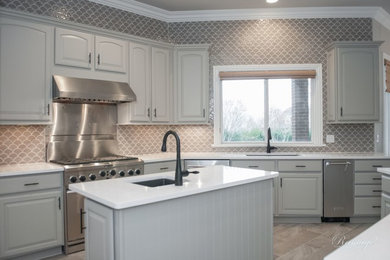 Example of a mid-sized classic galley porcelain tile and gray floor open concept kitchen design in Other with a single-bowl sink, raised-panel cabinets, gray cabinets, quartzite countertops, beige backsplash, ceramic backsplash, stainless steel appliances, an island and white countertops