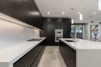 Large minimalist l-shaped porcelain tile and gray floor eat-in kitchen photo in Orange County with an undermount sink, flat-panel cabinets, dark wood cabinets, quartzite countertops, white backsplash, ceramic backsplash, paneled appliances, an island and white countertops