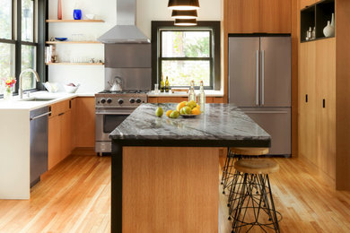 Foto på ett funkis kök, med en undermonterad diskho, släta luckor, skåp i mellenmörkt trä, marmorbänkskiva, rostfria vitvaror, mellanmörkt trägolv och en köksö