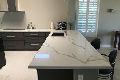 Example of a mid-sized minimalist u-shaped porcelain tile and white floor open concept kitchen design in Phoenix with an undermount sink, flat-panel cabinets, dark wood cabinets, marble countertops, stainless steel appliances and an island