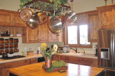 Eat-in kitchen - mid-sized rustic u-shaped eat-in kitchen idea in Denver with a double-bowl sink, raised-panel cabinets, medium tone wood cabinets, wood countertops, black backsplash, stone tile backsplash and stainless steel appliances