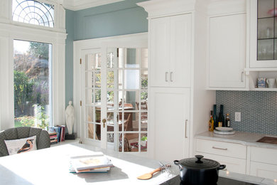 Klassisk inredning av ett mellanstort kök, med en dubbel diskho, skåp i shakerstil, vita skåp, marmorbänkskiva, grönt stänkskydd, stänkskydd i glaskakel, rostfria vitvaror, mellanmörkt trägolv och en köksö