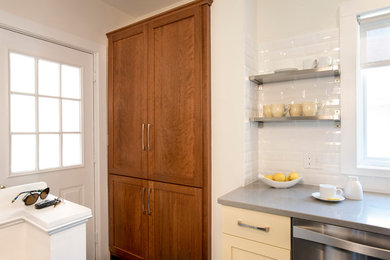 Example of a large transitional galley dark wood floor and brown floor eat-in kitchen design in Boston with a drop-in sink, shaker cabinets, yellow cabinets, solid surface countertops, white backsplash, subway tile backsplash, stainless steel appliances and a peninsula