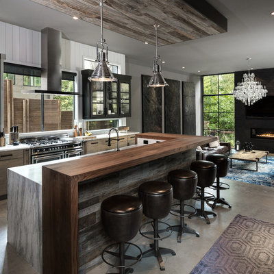 Inspiration for a large industrial galley concrete floor and gray floor open concept kitchen remodel in Dallas with flat-panel cabinets, light wood cabinets, marble countertops, white backsplash, wood backsplash, an island and black appliances