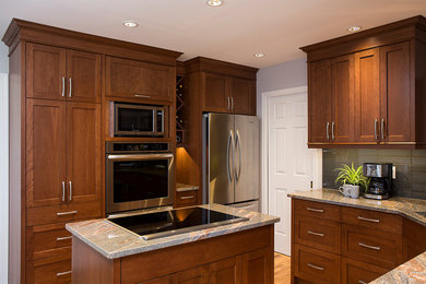 Example of a transitional light wood floor kitchen design in Vancouver with a double-bowl sink, shaker cabinets, dark wood cabinets, granite countertops, gray backsplash, glass tile backsplash, stainless steel appliances and an island
