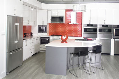 Trendy l-shaped kitchen photo in Charlotte with a single-bowl sink, flat-panel cabinets, white cabinets, quartz countertops, red backsplash, ceramic backsplash and stainless steel appliances