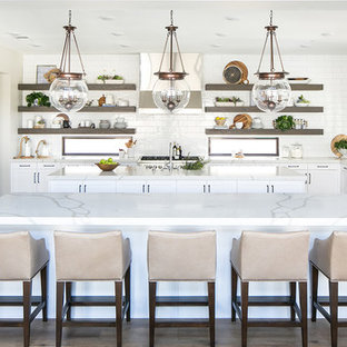 Coastal kitchen designs - Beach style medium tone wood floor kitchen photo in San Diego with white cabinets, white backsplash, subway tile backsplash, two islands, a farmhouse sink, shaker cabinets, stainless steel appliances and white countertops