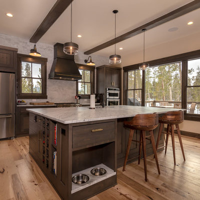 Example of a large mountain style l-shaped light wood floor and beige floor open concept kitchen design in Denver with an undermount sink, shaker cabinets, dark wood cabinets, quartz countertops, beige backsplash, subway tile backsplash, stainless steel appliances, an island and white countertops