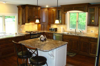 Example of a mid-sized classic u-shaped dark wood floor and brown floor enclosed kitchen design in Other with a double-bowl sink, raised-panel cabinets, dark wood cabinets, granite countertops, beige backsplash, stone tile backsplash, stainless steel appliances and an island