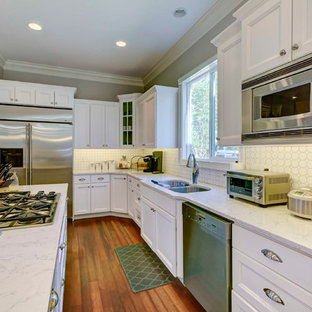 Small transitional galley eat-in kitchen in Raleigh with a double-bowl sink, recessed-panel cabinets, white cabinets, quartzite benchtops, white splashback, ceramic splashback, stainless steel appliances, medium hardwood floors and with island.