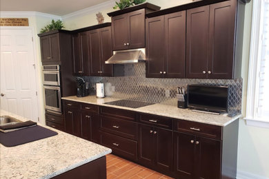 Kitchen pantry - mid-sized transitional l-shaped ceramic tile and brown floor kitchen pantry idea in Miami with a drop-in sink, recessed-panel cabinets, dark wood cabinets, quartz countertops, metallic backsplash, metal backsplash, stainless steel appliances, an island and multicolored countertops