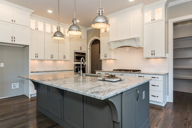 Photo of a classic l-shaped kitchen/diner in Raleigh with a submerged sink, grey cabinets, granite worktops, white splashback, metro tiled splashback, an island, shaker cabinets, stainless steel appliances and dark hardwood flooring.